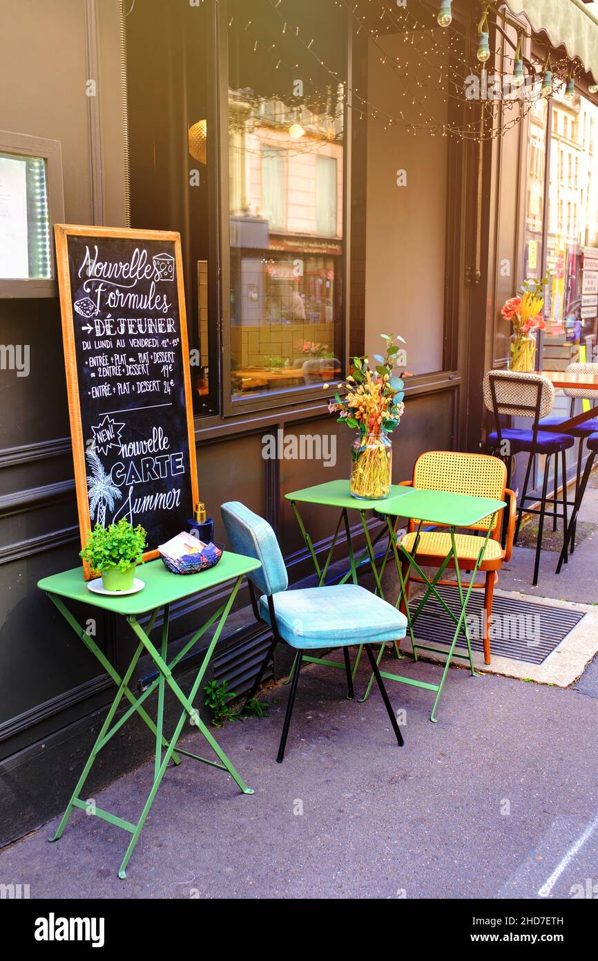 Pequeño restaurante francés - mesa y sillas decoradas con flores en la calle - París, Francia Foto de stock