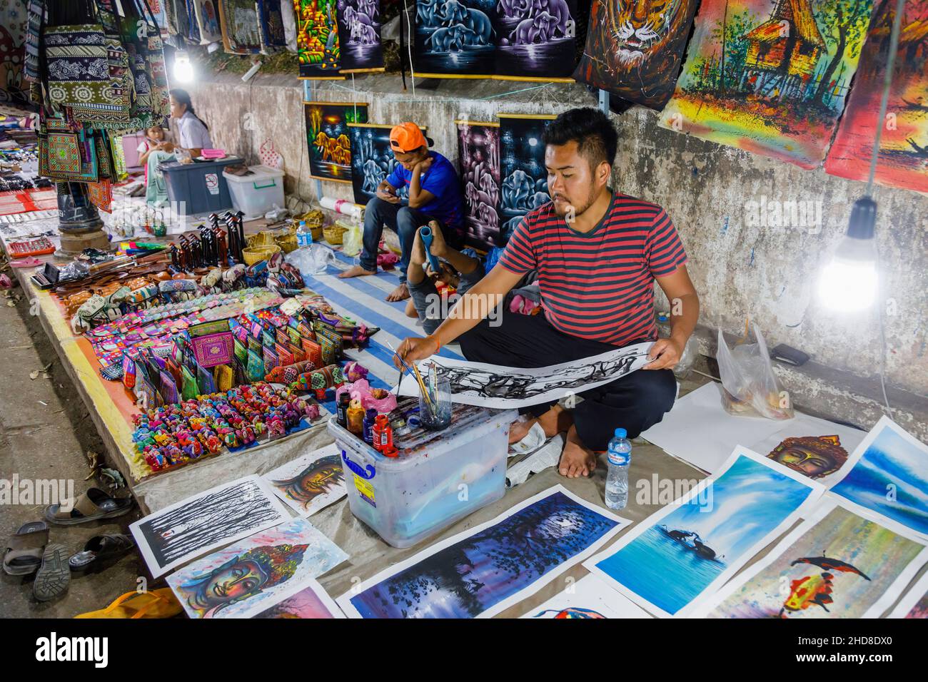 Un estallholder local pinta una foto de recuerdo en un puesto en el mercado nocturno de la calle peatonal en el centro de Luang Prabang, norte de Laos, sudeste asiático Foto de stock