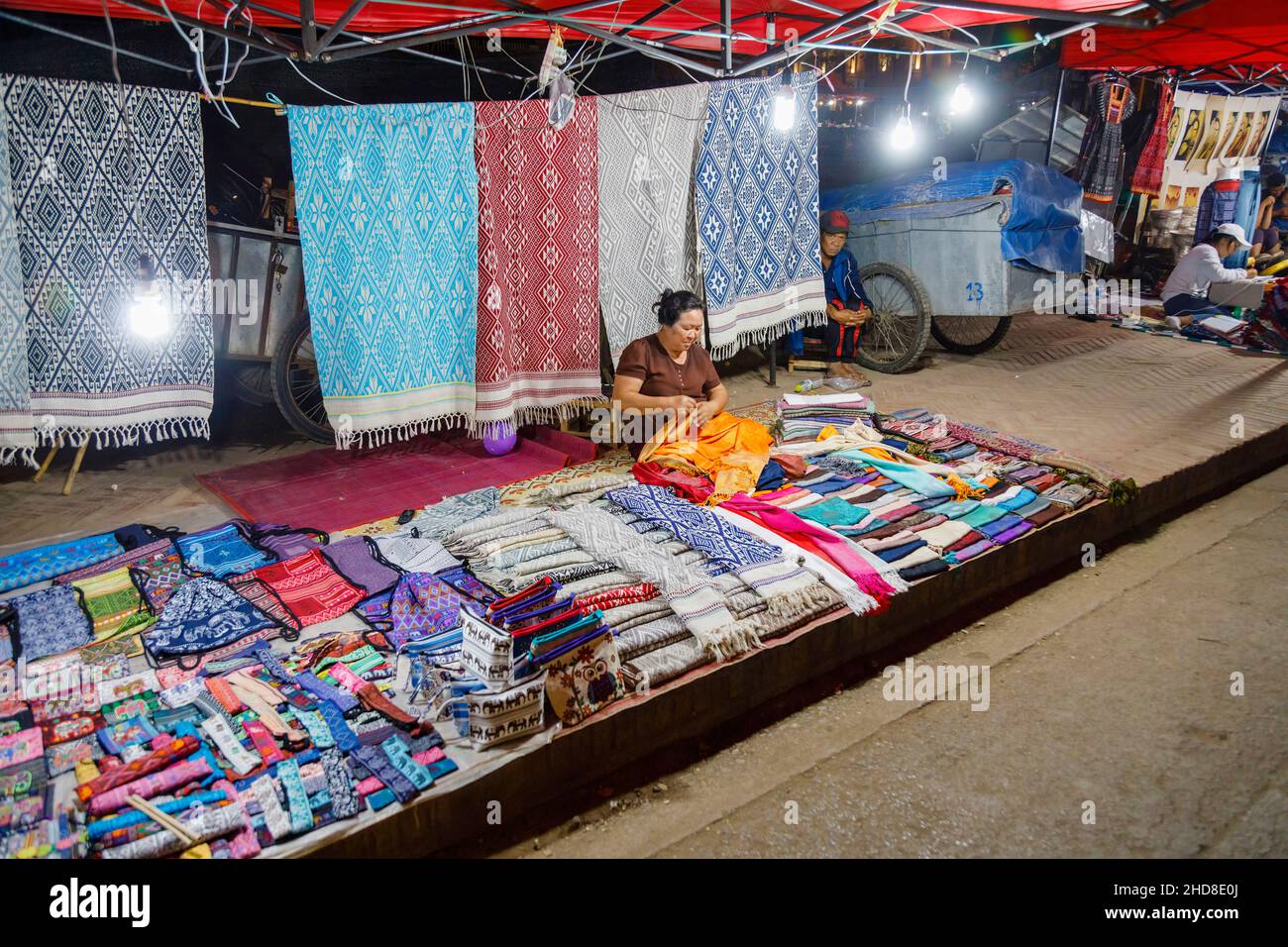 Estallholder femenino local que vende telas en el mercado nocturno de la calle peatonal en el centro de Luang Prabang, norte de Laos, sudeste de Asia Foto de stock
