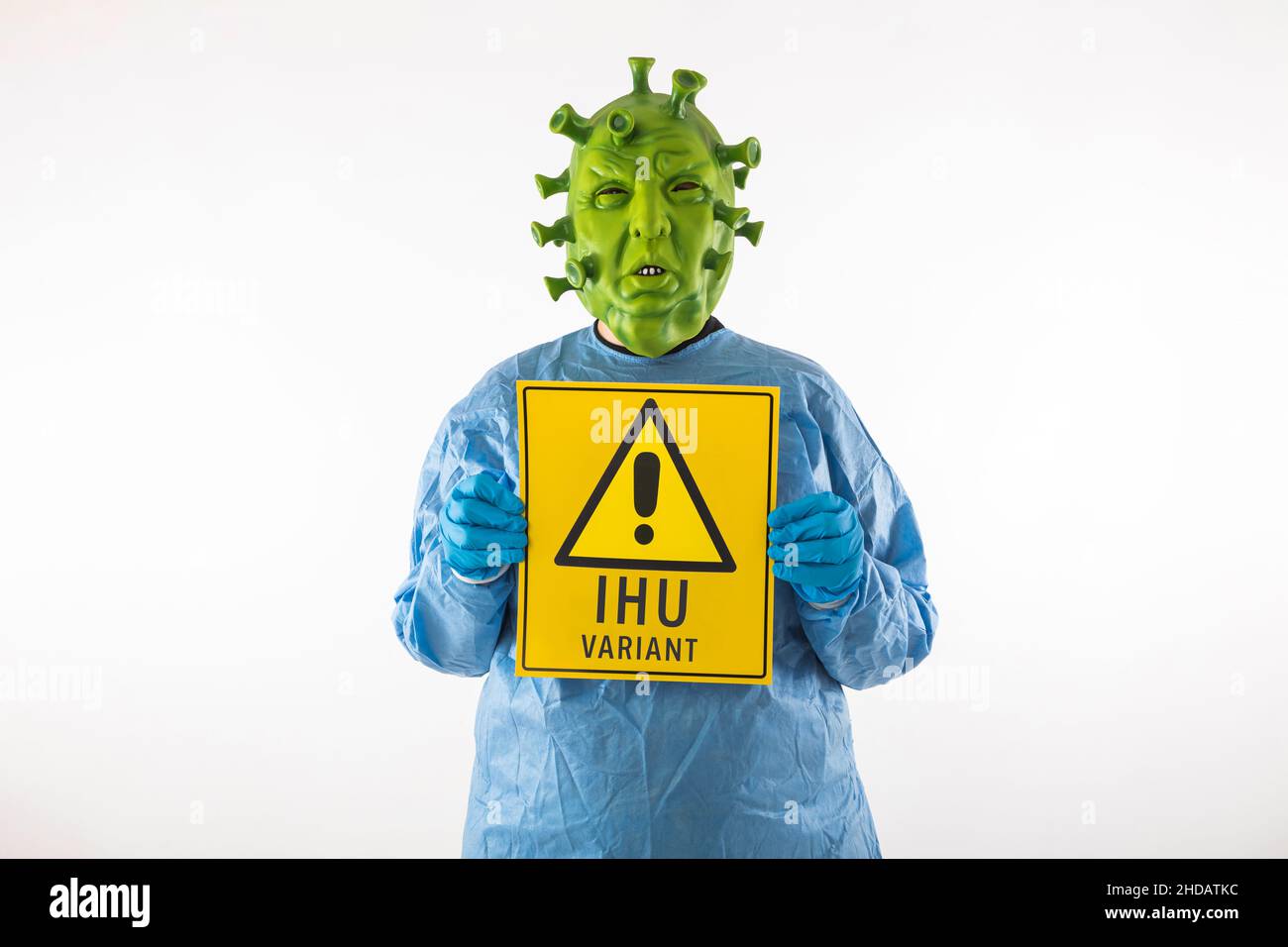 Hombre vestido con máscara de látex de coronavirus, EPI y guantes de látex,  sosteniendo una etiqueta de peligro IHU variante amarilla, sobre fondo  blanco. Coronavirus, salud, pa Fotografía de stock - Alamy