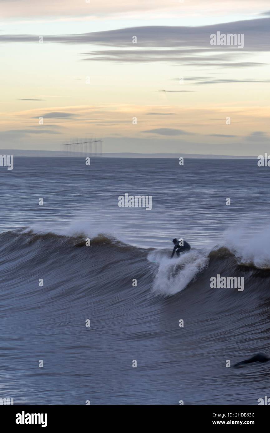 surfer en surf board montando una ola en saltburn, north yorkshire, reino unido Foto de stock