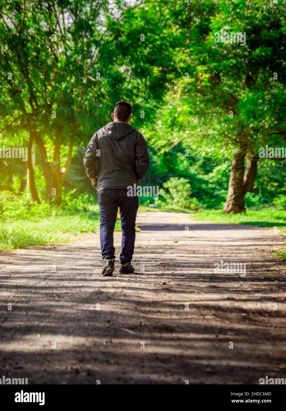 Hombre caminando por un camino desolado, hombre caminando hacia atrás en un  camino rodeado de vegetación Fotografía de stock - Alamy