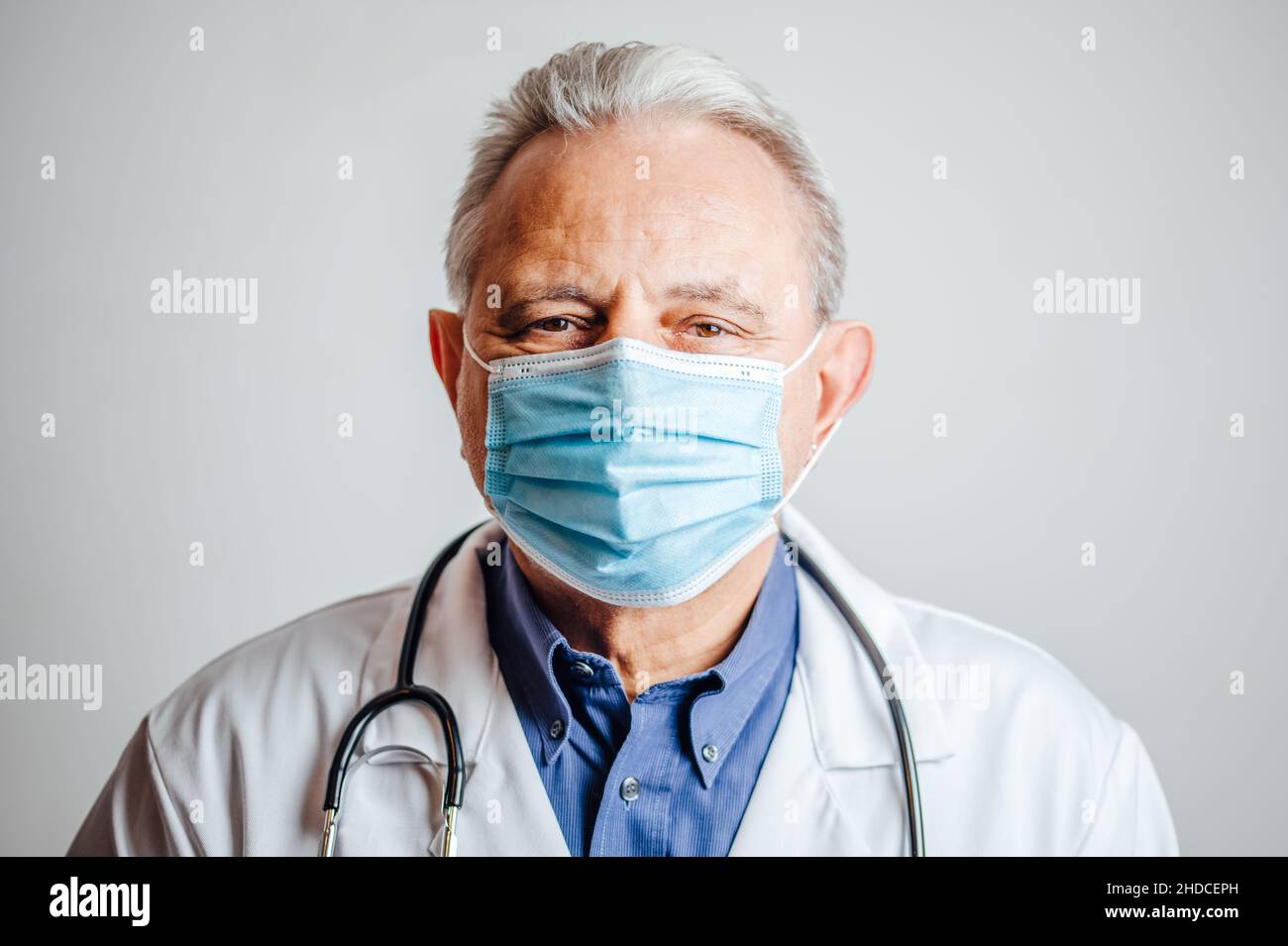 El médico lleva una mascarilla facial y un estetoscopio alrededor de los cuellos altos Foto de stock