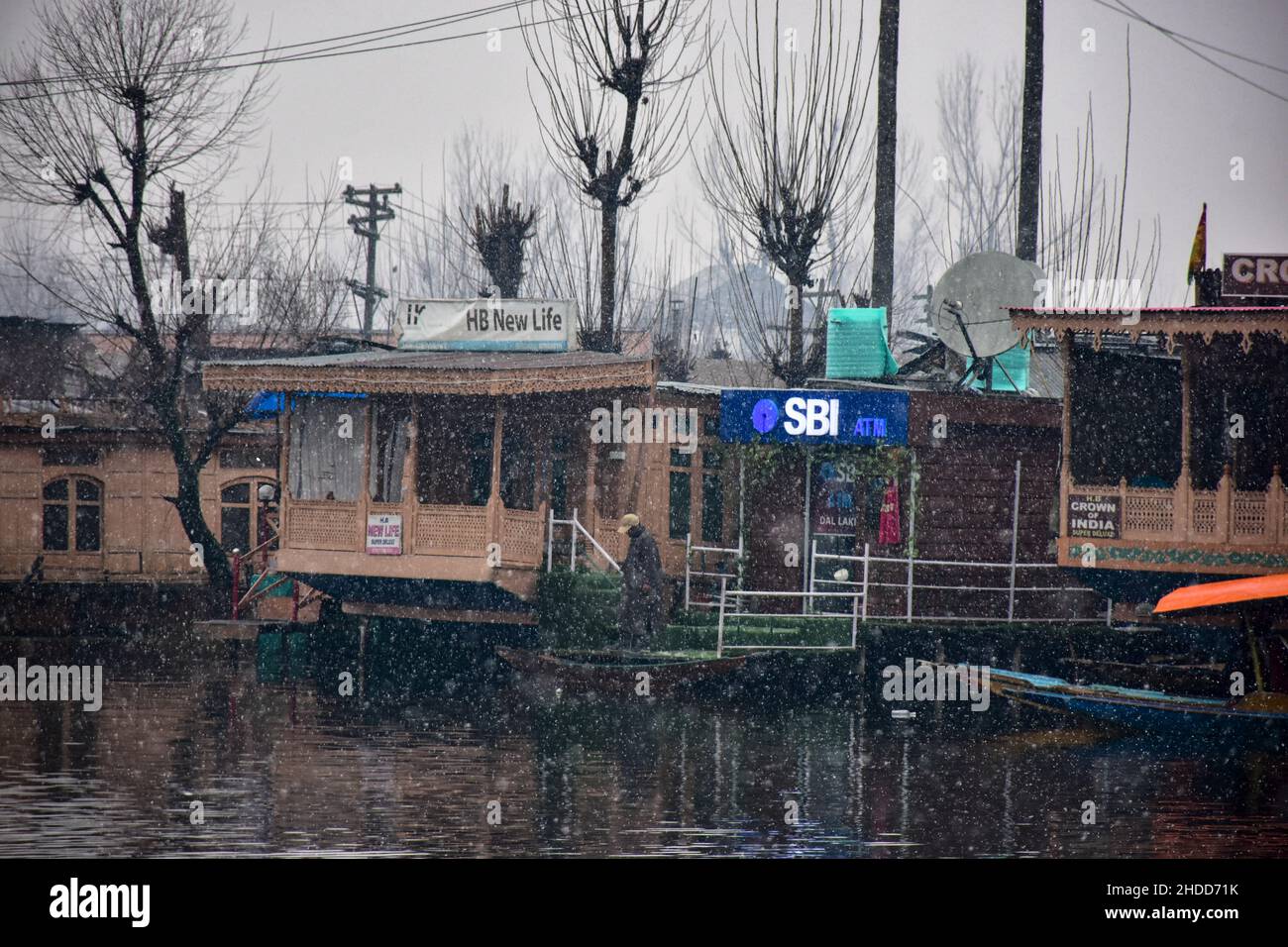Un hombre camina por la cubierta de la casa flotante durante una nevada en Srinagar.Cachemira ha registrado una lluvia y nieve generalizadas a moderadas, lo que ha dado lugar a vuelos de cancelación hacia y desde el aeropuerto internacional de Srinagar, mientras que varias zonas de flung lejano permanecieron cortadas el miércoles. El departamento de Meteorología dijo que están esperando una 'nevada fuerte' el 7th-8th de este mes. Foto de stock