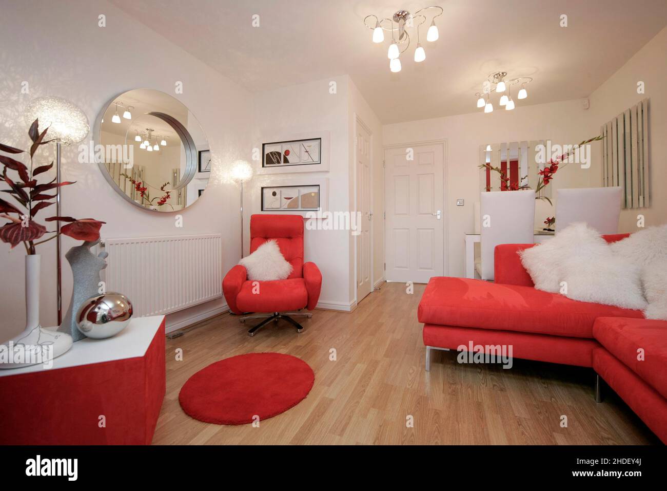 Salón moderno con suelo laminado de efecto madera y sofá de esquina, silla,  muebles de color rojo escarlata. Decoración roja. Mesa de comedor blanca  Fotografía de stock - Alamy