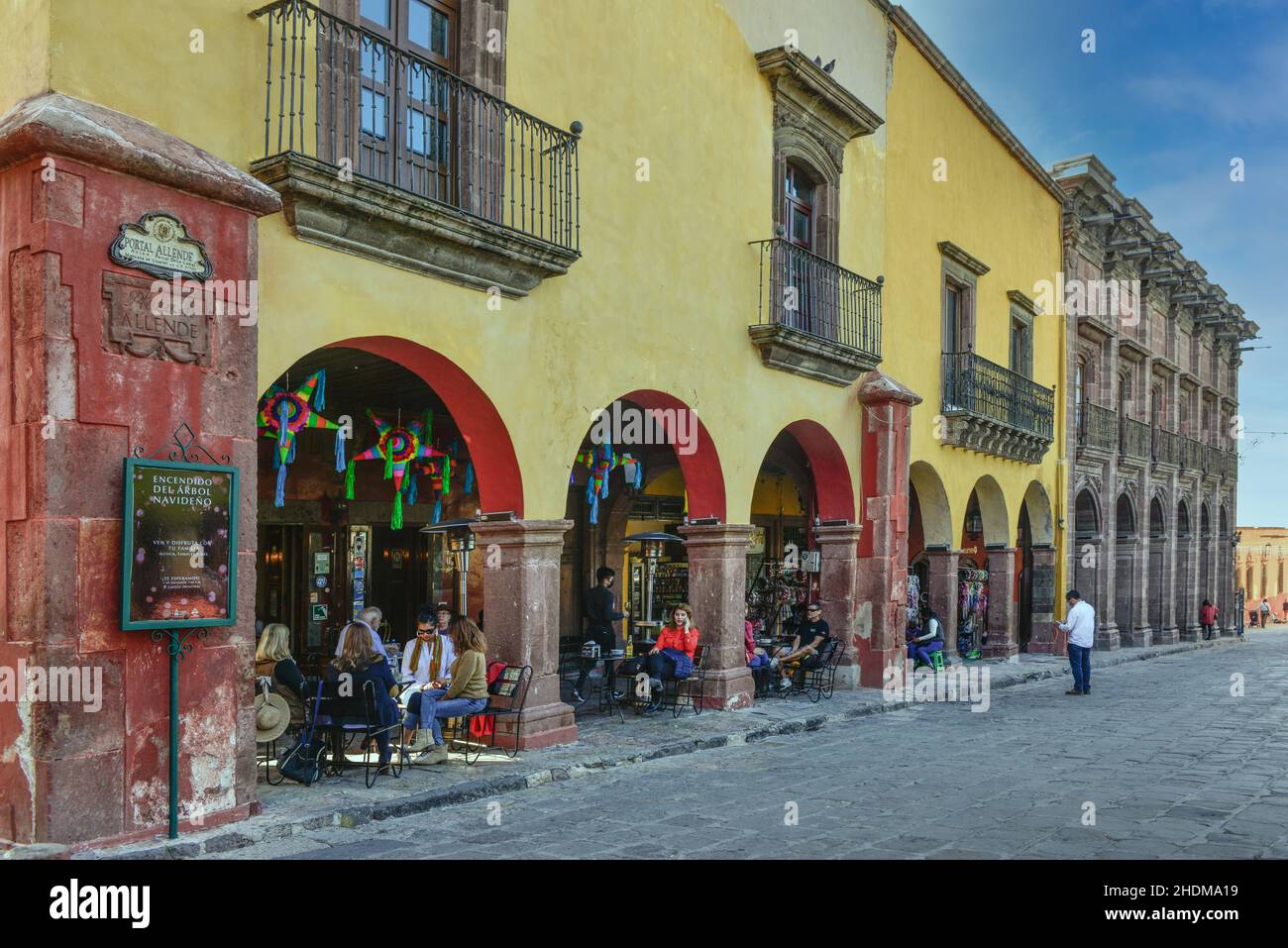 La gente se relaja alrededor de los cafés y restaurantes al aire libre en el distrito central a lo largo del portal Allende, en la colonial San Miguel de Allende, MX Foto de stock