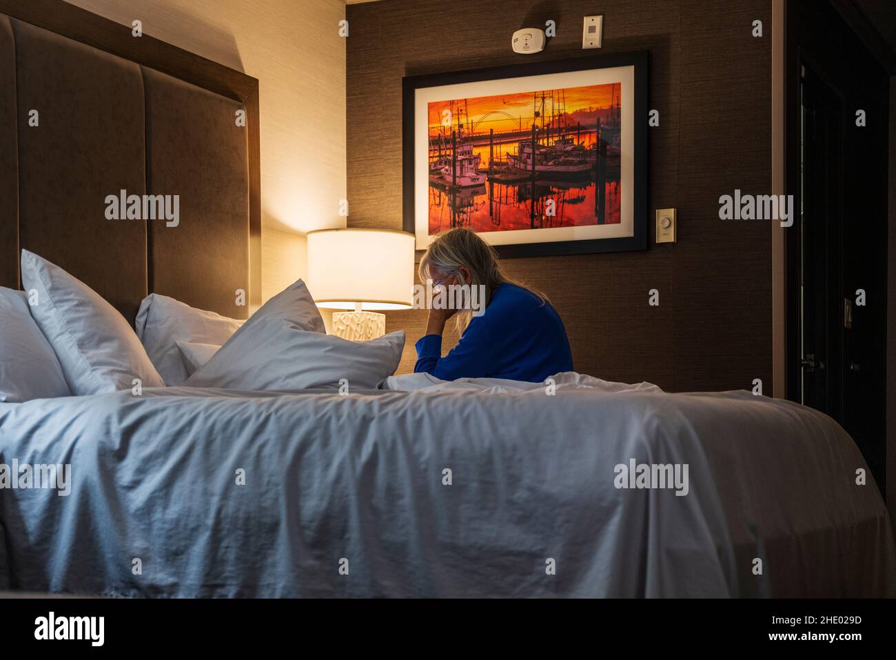 Mujer mayor leyendo en la cama; habitación de hotel; Newport; Oregon; Estados Unidos Foto de stock