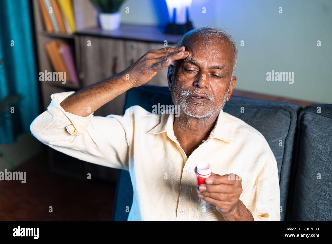 Hombre mayor que usa bálsamo para el alivio del dolor de cabeza - concepto de pomada de masaje para la migraña, alivio del estrés y analgésico. Foto de stock