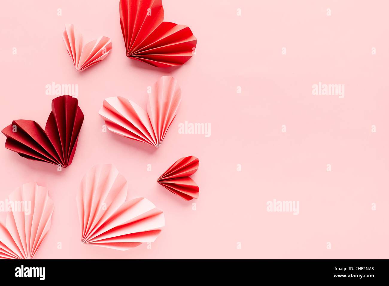 Corazones de papel sobre fondo rosa. Símbolo de amor por el día de San  Valentín, feliz cumpleaños, saludos, Día de la Madre, Día de la Mujer.  Origami Fotografía de stock - Alamy