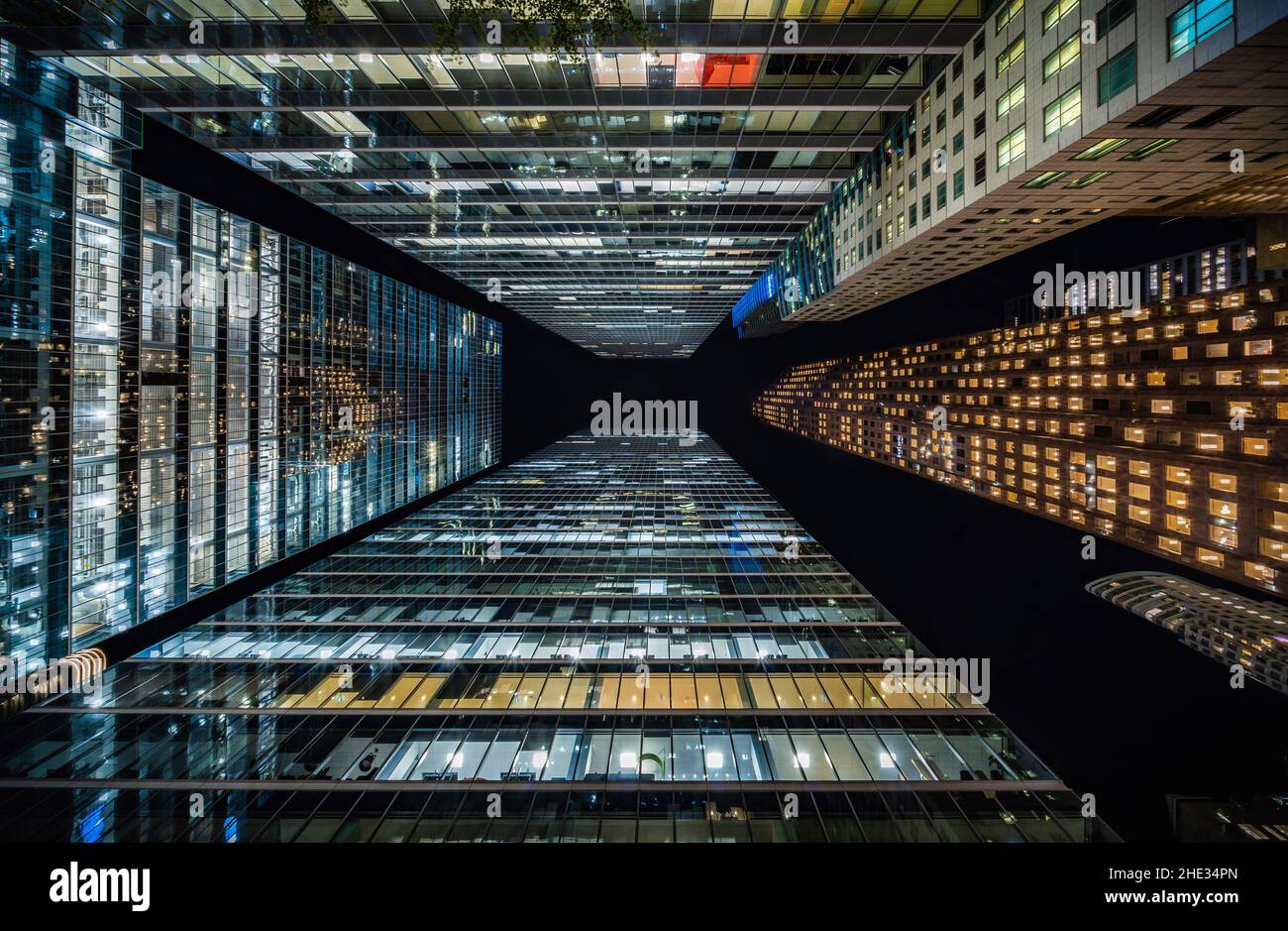 Concepto de negocios y finanzas, mirando la arquitectura de edificios de oficinas de gran altura por la noche en el distrito financiero de una metrópolis moderna. Foto de stock