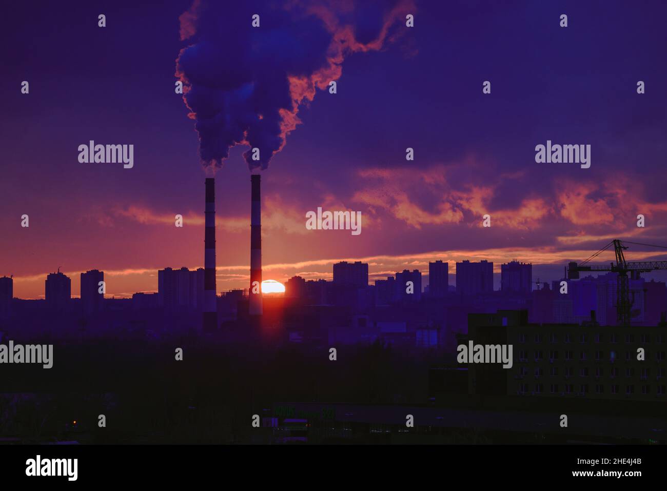 Chimeneas de fumar en una ciudad a la puesta de sol escénica Foto de stock