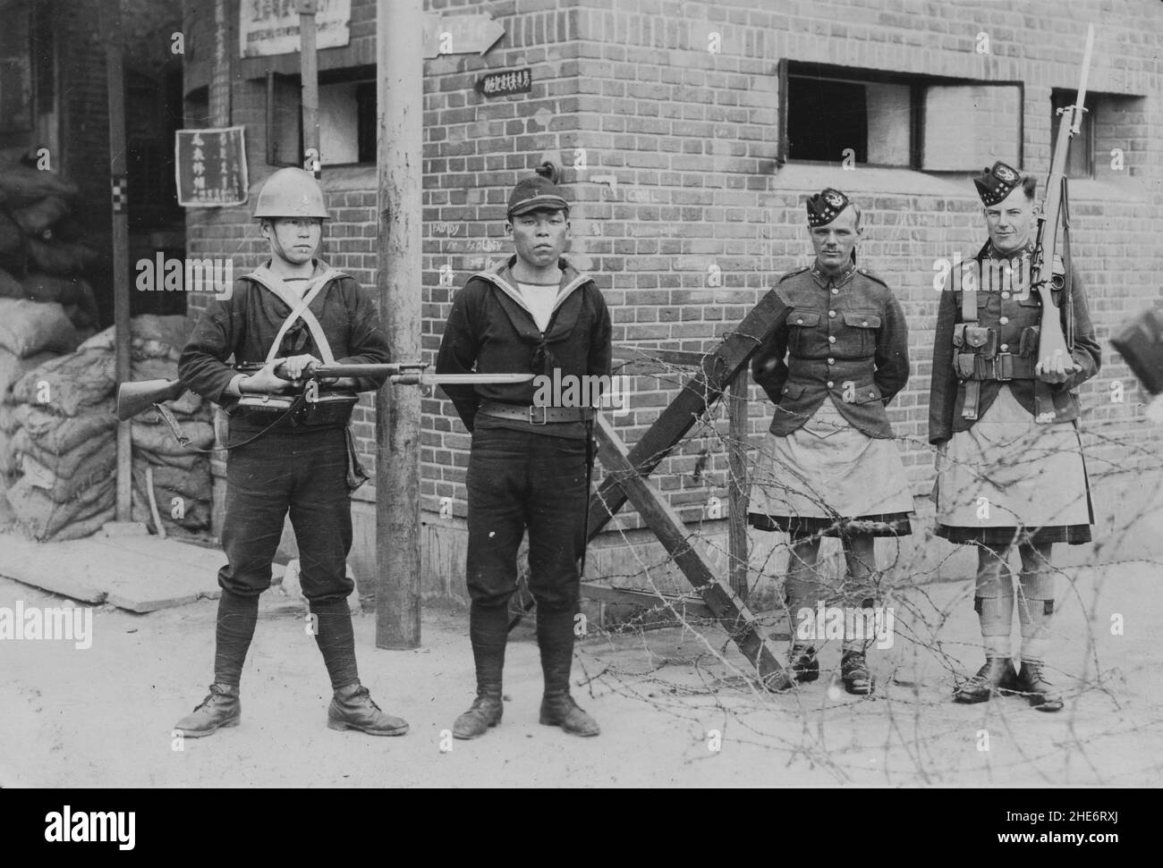 Segunda Guerra Sino-Japonesa, 1937-1945. Dos miembros de la Fuerza Naval Especial Japonesa se ponen de guardia en una barricada en el asentamiento internacional, acompañados por dos hombres de la Compañía Escocesa del Cuerpo de Voluntarios de Shanghai, alrededor de 1938. Durante la Batalla de Shanghai, la Fuerza Naval Especial Japonesa participó en intensos combates contra el Ejército Revolucionario Nacional de Chiang Kai-shek entre agosto y noviembre de 1937. La Fuerza Especial de Desembarque Naval de Japón ocupó más tarde todo el Acuerdo Internacional tras el estallido de la Guerra del Pacífico el 7th de diciembre de 1941. Foto de stock