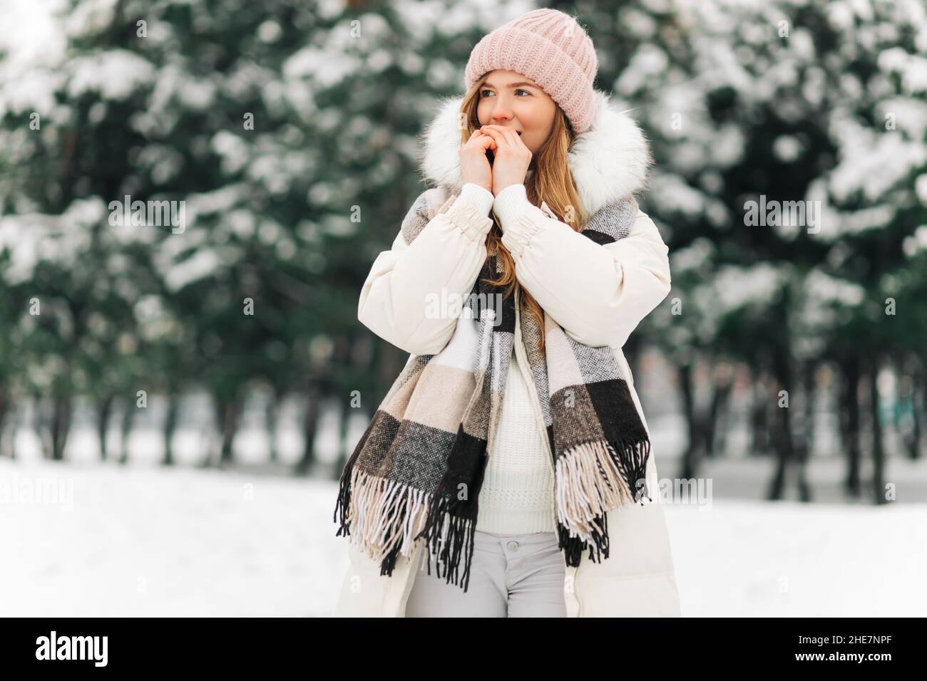 Retrato de una mujer de invierno con ropa de abrigo, la mujer respira en  sus brazos para mantenerlos calientes en un frío día de invierno, hermosa  mujer joven al aire libre. Frío