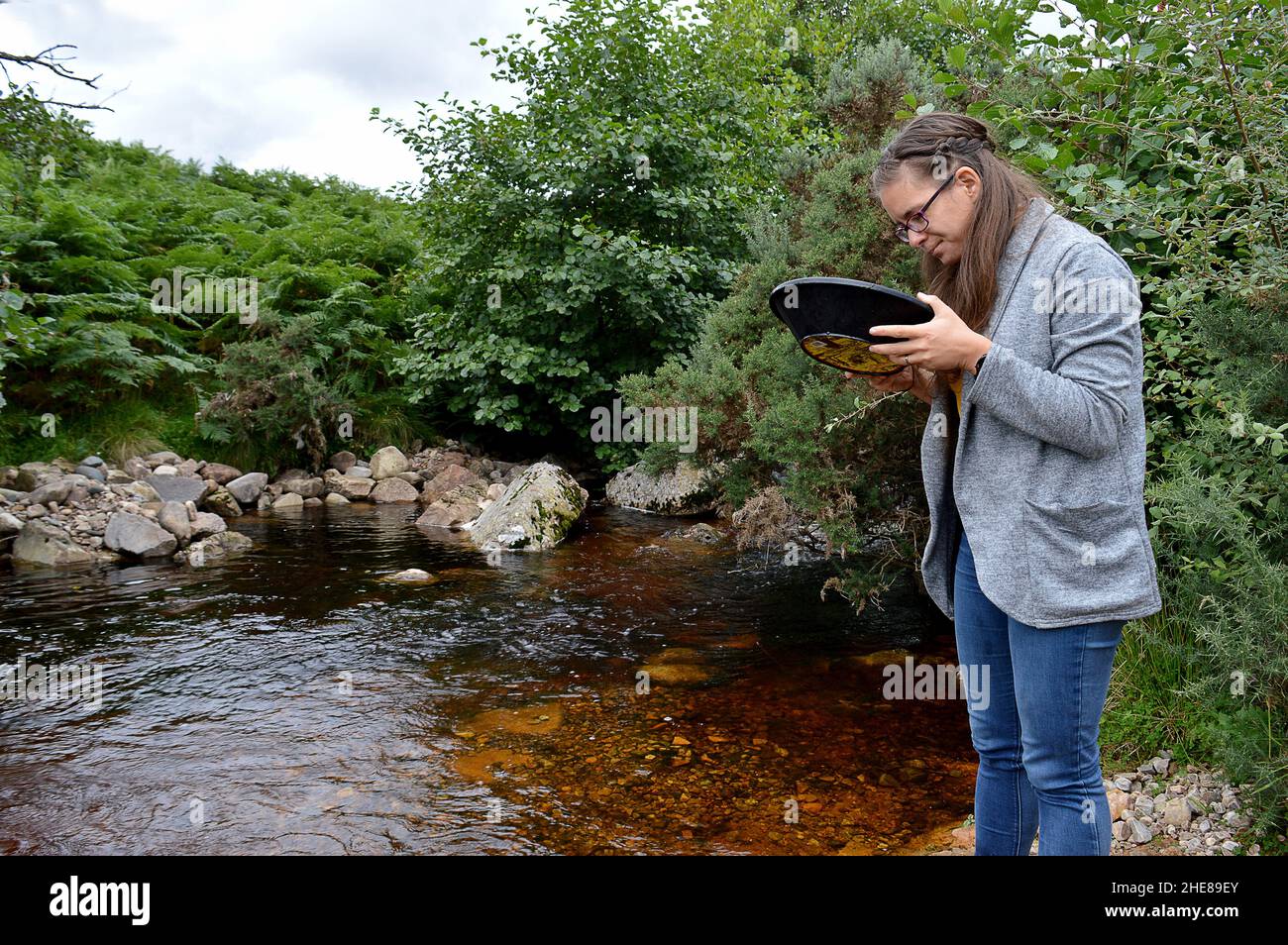 Mujer joven buscando oro en el Kildonan Burn cerca de Helmsdale, Sutherland, Escocia Foto de stock