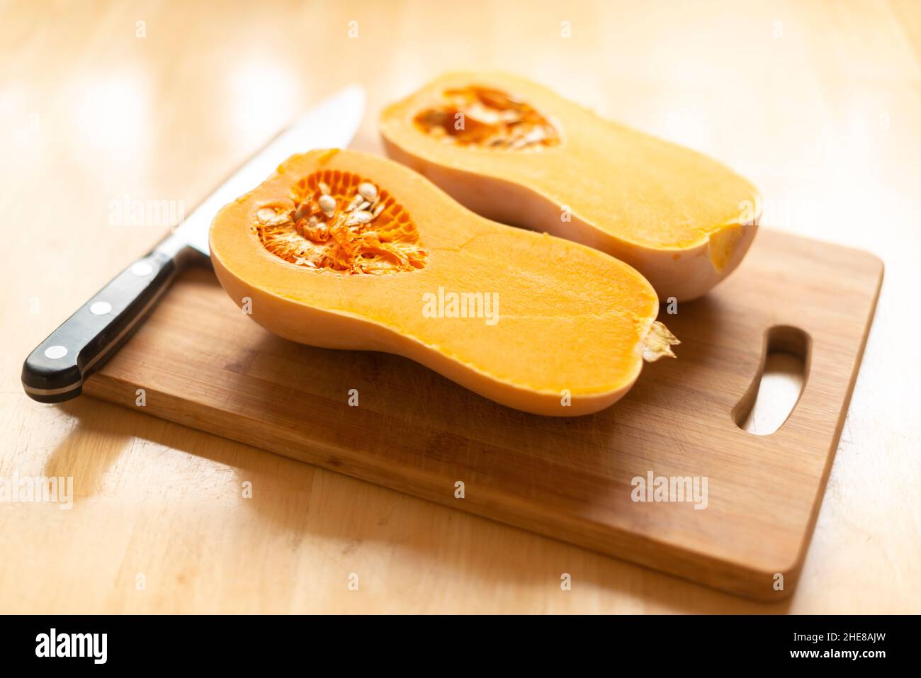 Calabaza de butternut (Cucurbita moschata)-mcut por la mitad en una tabla de cortar-enfoque selectivo Foto de stock