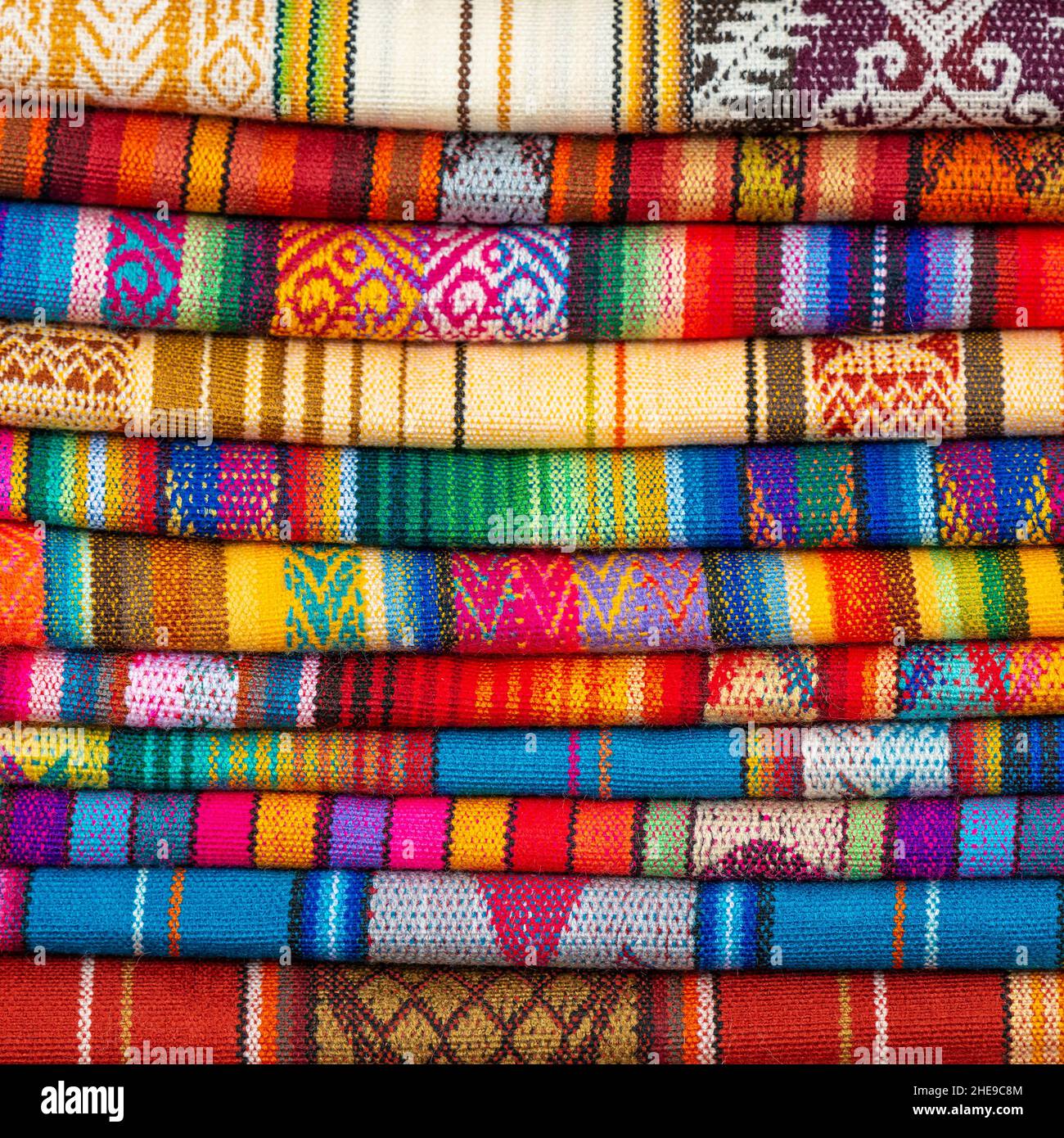 Pila de coloridos textiles o telas indígenas andinos, mercado de Otavalo cerca de Quito, Ecuador. Foto de stock