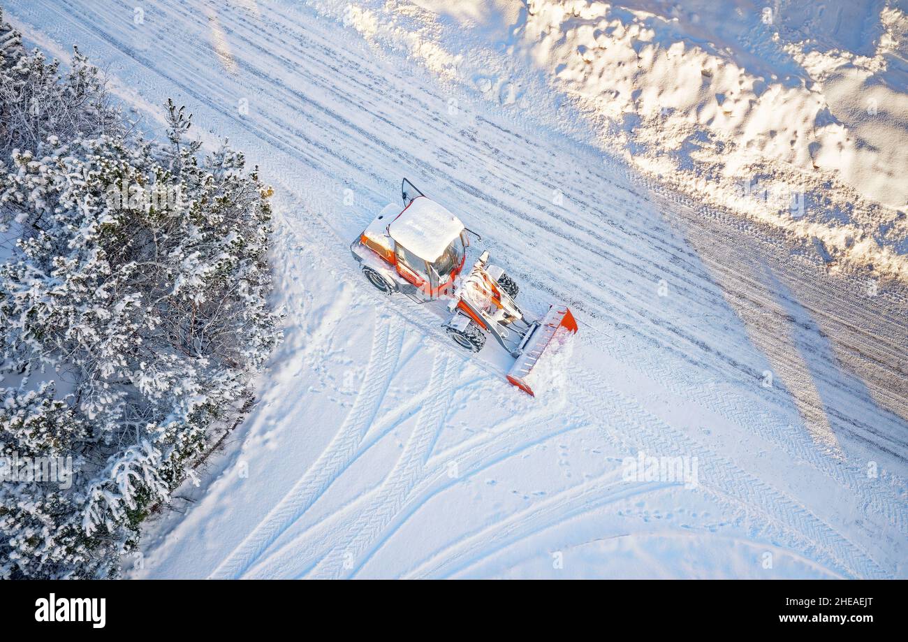 Retirada de nieve con el tractor rojo en carretera. SUNY día de invierno, Drone vista superior. Antena. Vista desde arriba. Foto de stock
