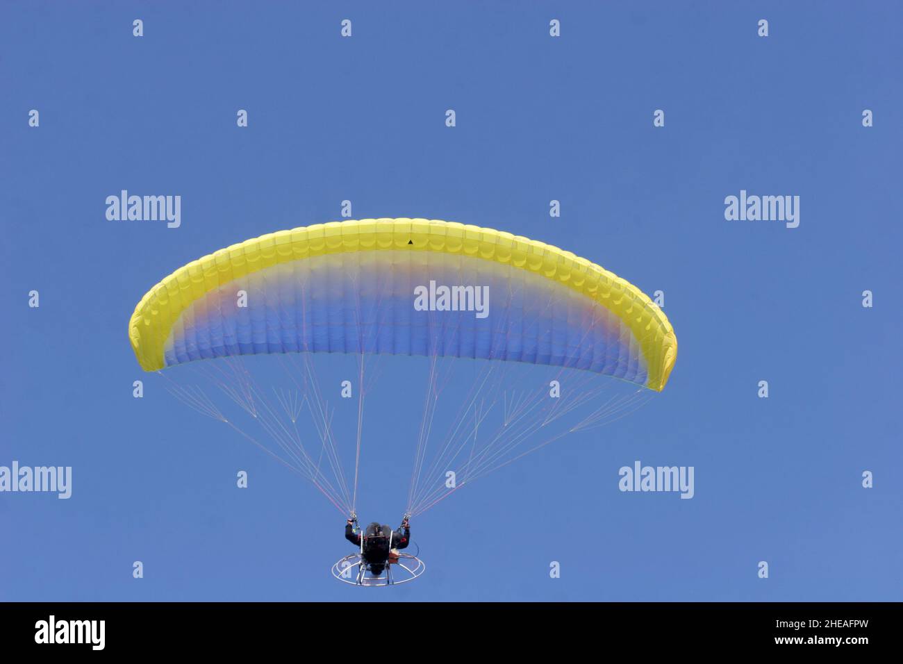 Parapente en un cielo azul. Deporte en el que los jugadores vuelan en el aire usando parapente. Foto de stock
