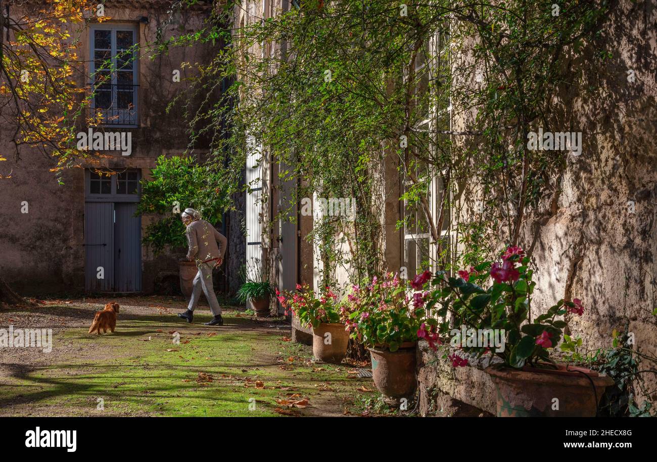 Francia, Herault, Pezenas, anciana en el patio de un antiguo edificio histórico rural Foto de stock