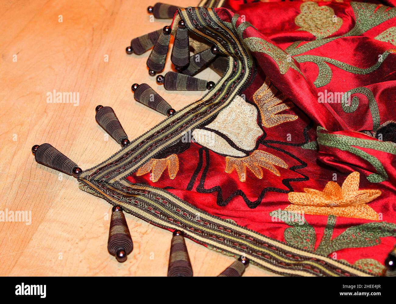 Manta bordada de colores vivos con unas exclusivas brazaletes que se muestran artísticamente sobre el fondo de madera Foto de stock