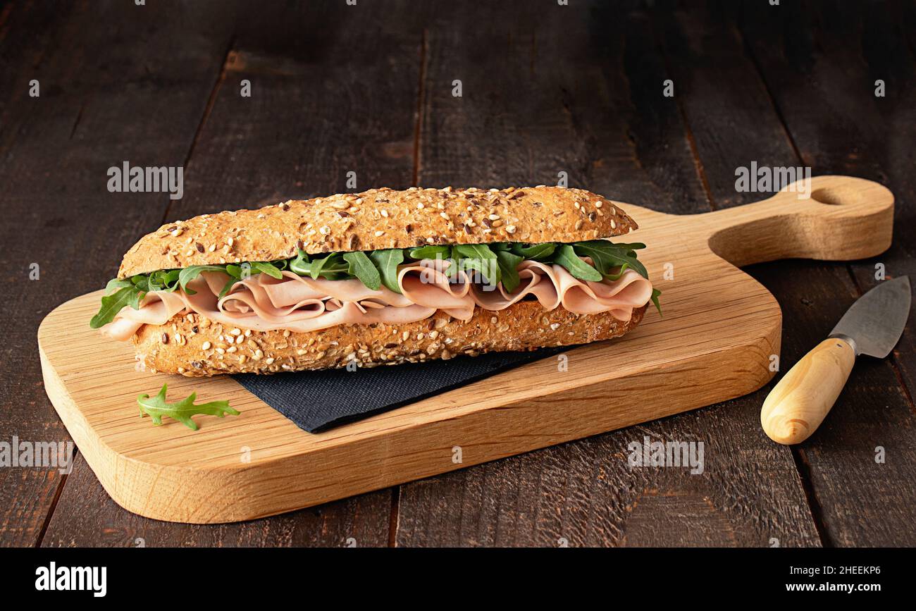 Sándwich de jamón mortadella con hojas de cohete sobre tabla de corte