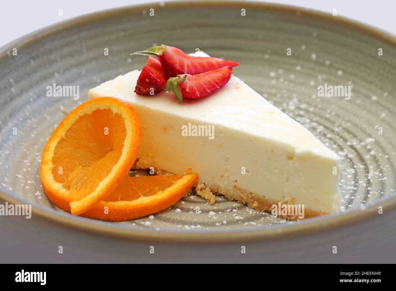 Tarta de queso con fresa y naranja en el plato de cerca. Foto de stock