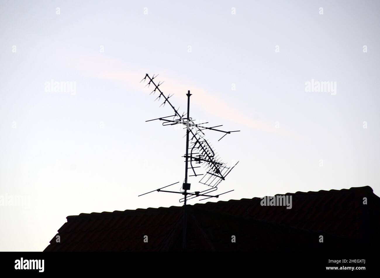 Silueta de la antena de TV UHF dañada por la tormenta en un techo. Foto de stock