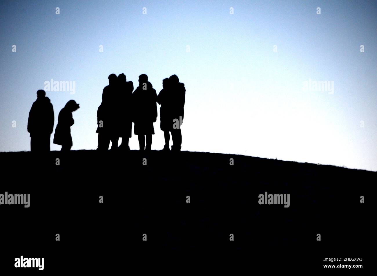Siluetas de personas de pie en grupo en la cima de una colina Foto de stock