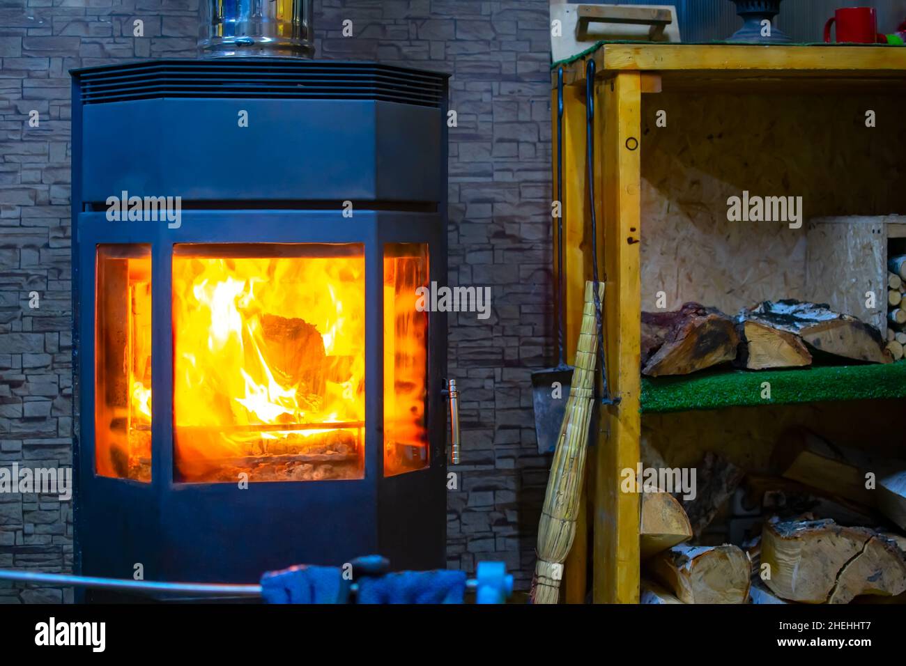 vista de un horno de metal con vidrio refractario templado, en el que se quema una llama brillante de fuego Foto de stock