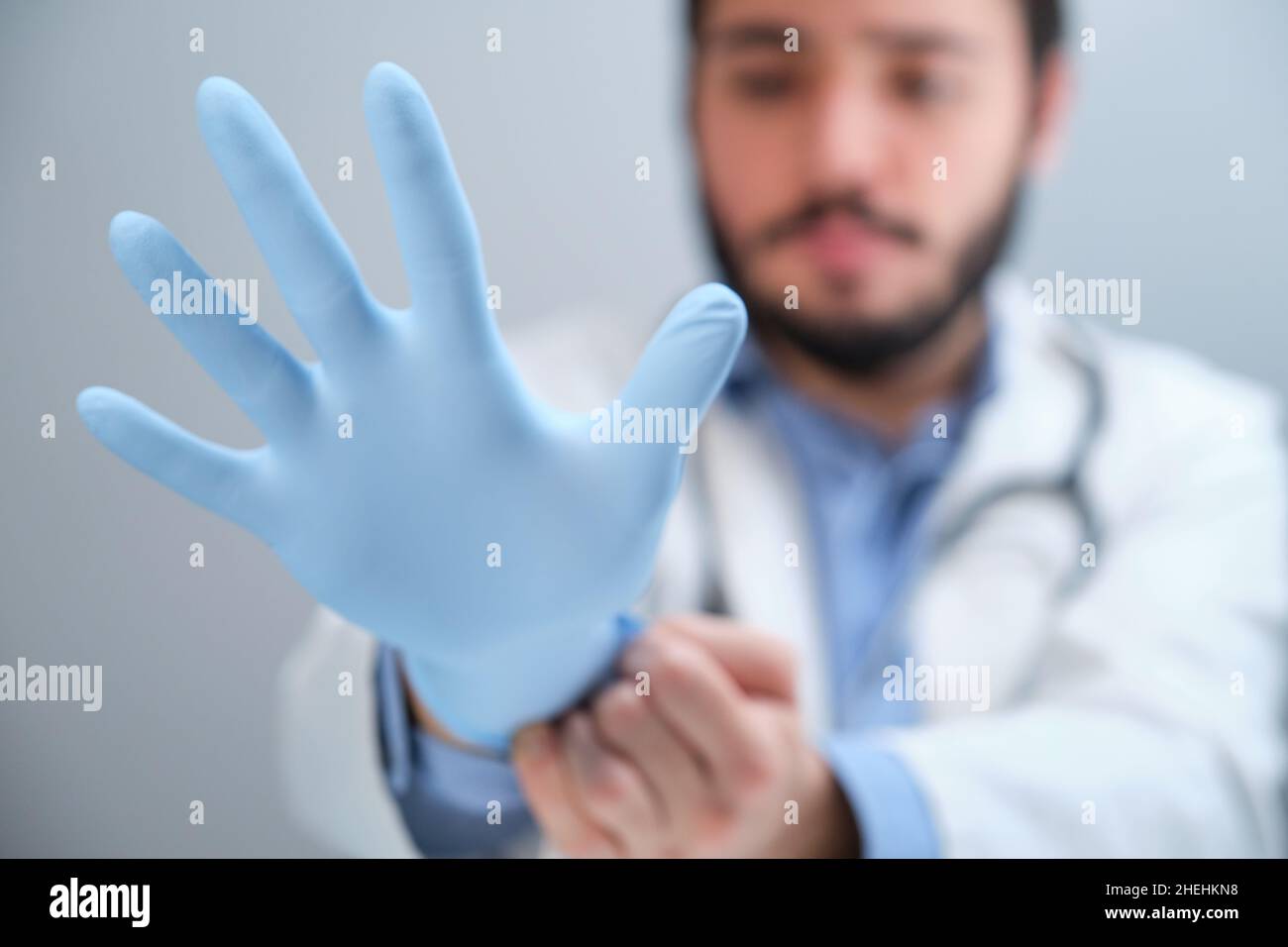 Médico irreconocible que se pone un guante azul. Foto de stock