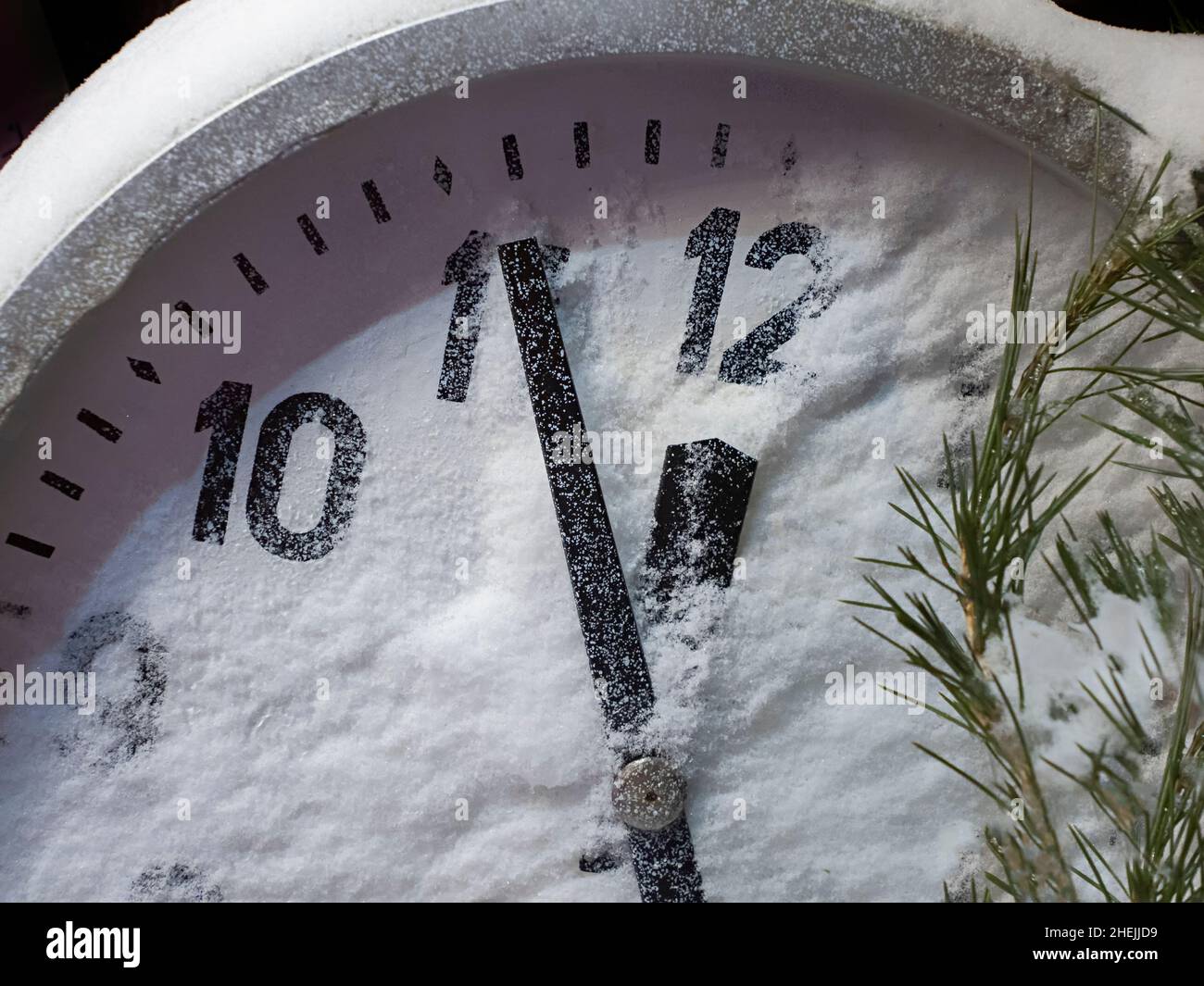 Las manos del reloj van a la medianoche, la cuenta atrás para el Año Nuevo, el dial está cubierto de nieve Foto de stock