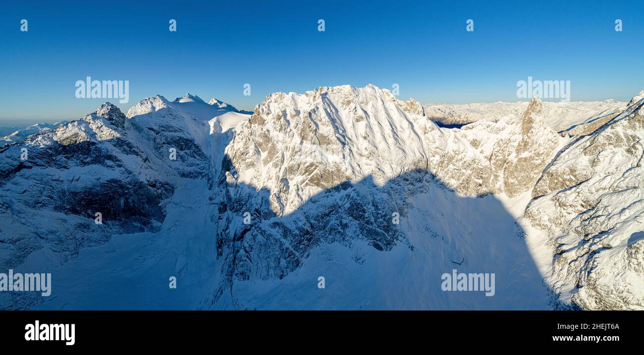 Vista aérea del claro cielo invernal sobre la montaña Sciora di Dentro cubierta de nieve, Val Bregaglia, Graubunden, Suiza Foto de stock