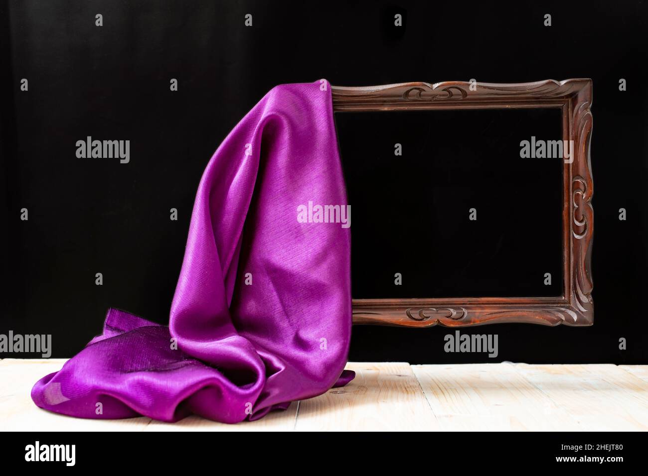 tejido sedoso que revela un marco de madera levitante, sobre fondo negro Foto de stock