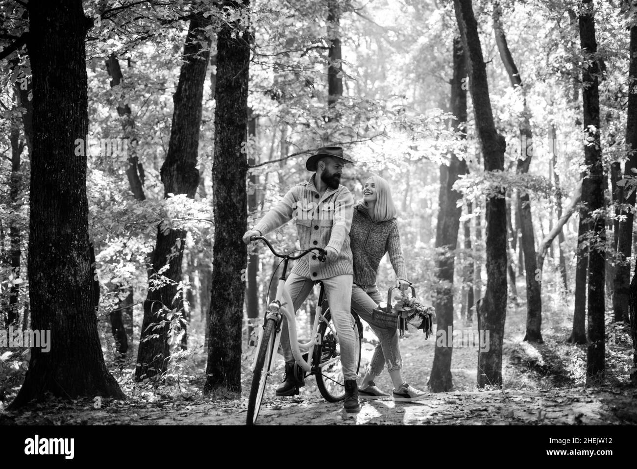 Pareja en el amor montar en bicicleta juntos en el parque forestal. Cita romántica con bicicleta. Hombre y mujer barbudos relajándose en el bosque otoñal. Una pareja romántica Foto de stock