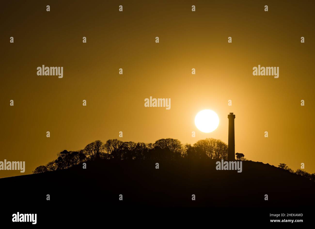 Puesta de sol en el claro cielo naranja con la silueta de la torre del Monumento a la cima de la colina de Hopetoun, East Lothian, Escocia, Reino Unido Foto de stock