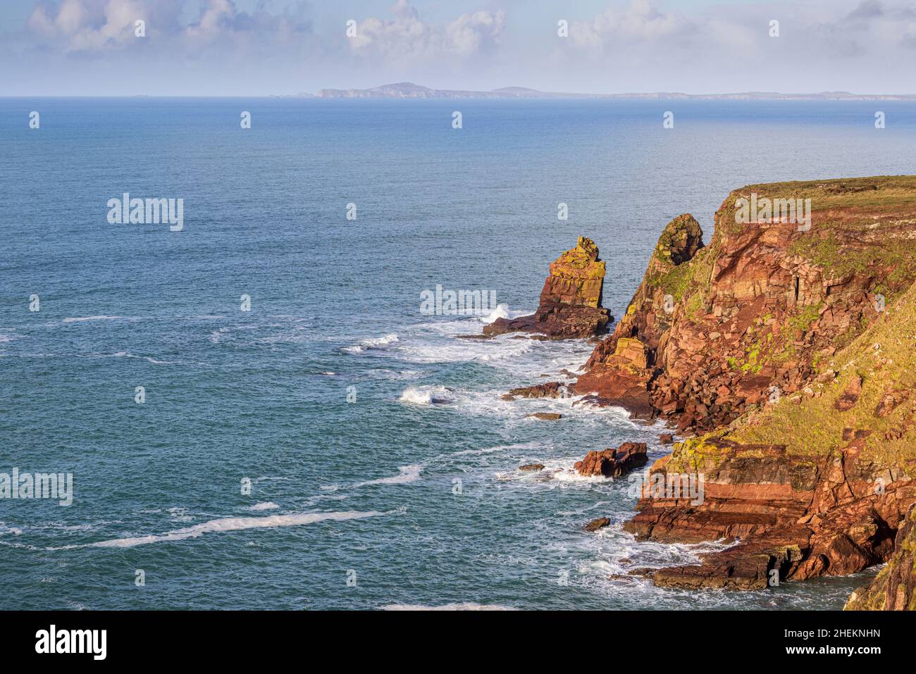 Los acantilados de arenisca de la bahía de St Brides con las montañas de St Davids Head en el fondo, Parque Nacional de la costa de Pembrokeshire, Gales del Sur Foto de stock