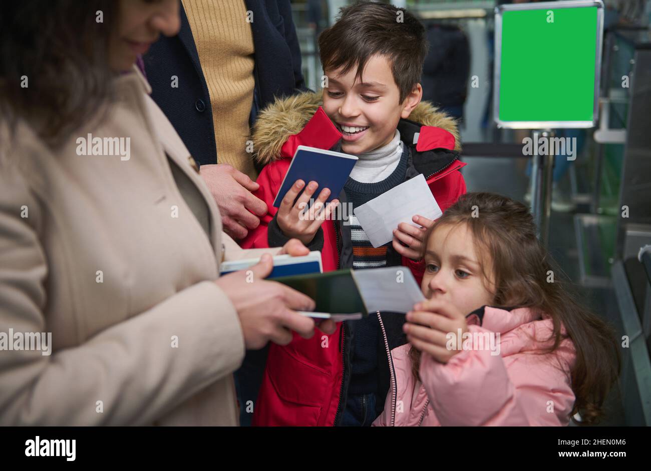 Niños alegres que disfrutan de viajes familiares, dando pasaportes a su madre mientras pasan el pasaporte y el control de aduanas en el aeropuerto. Viaje en avión Foto de stock