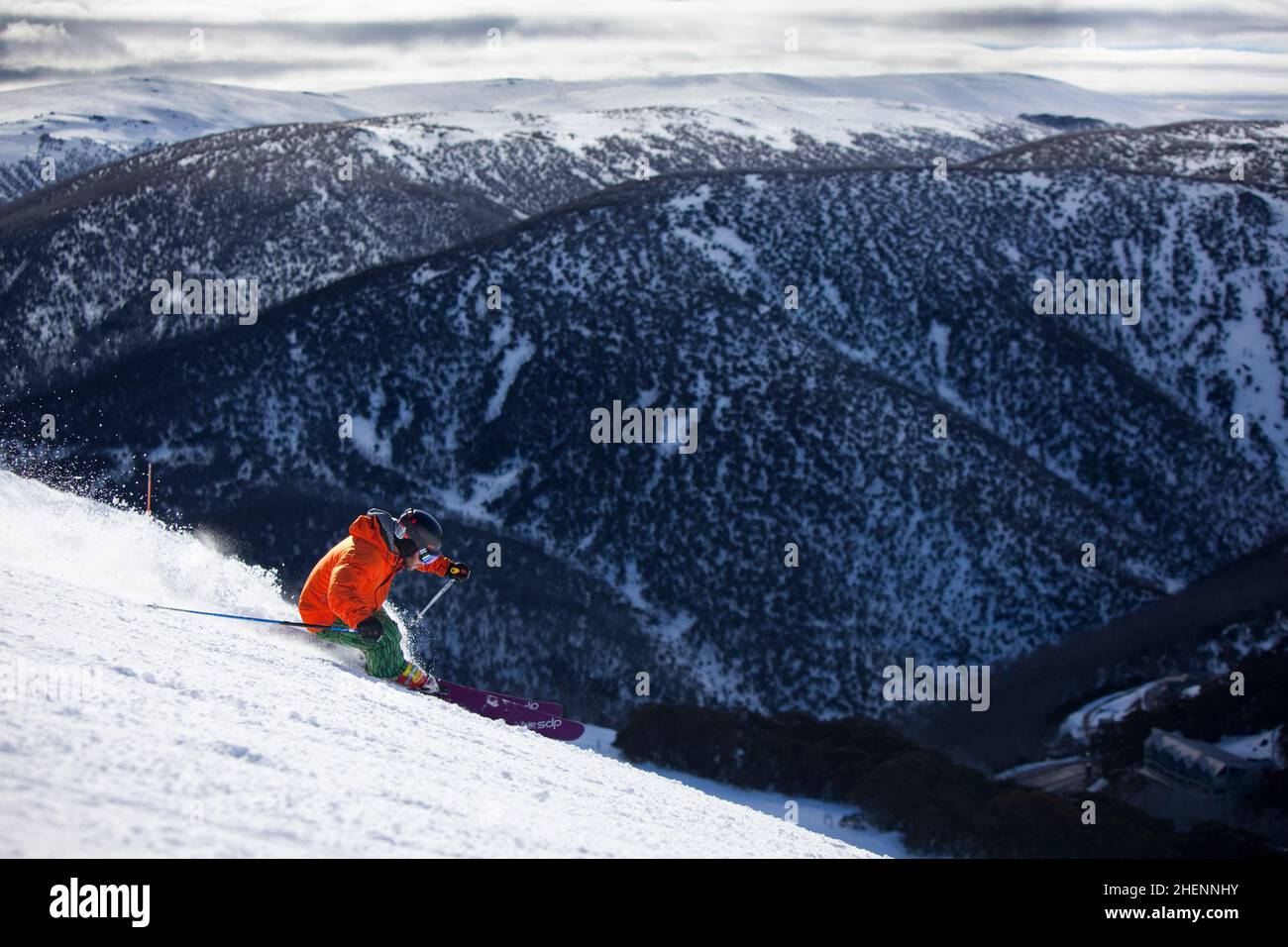 El esquiador alpino corre por 'The Slot' en Falls Creek Ski Resort, el Bogong High Plains cargado de nieve en la distancia. Foto de stock