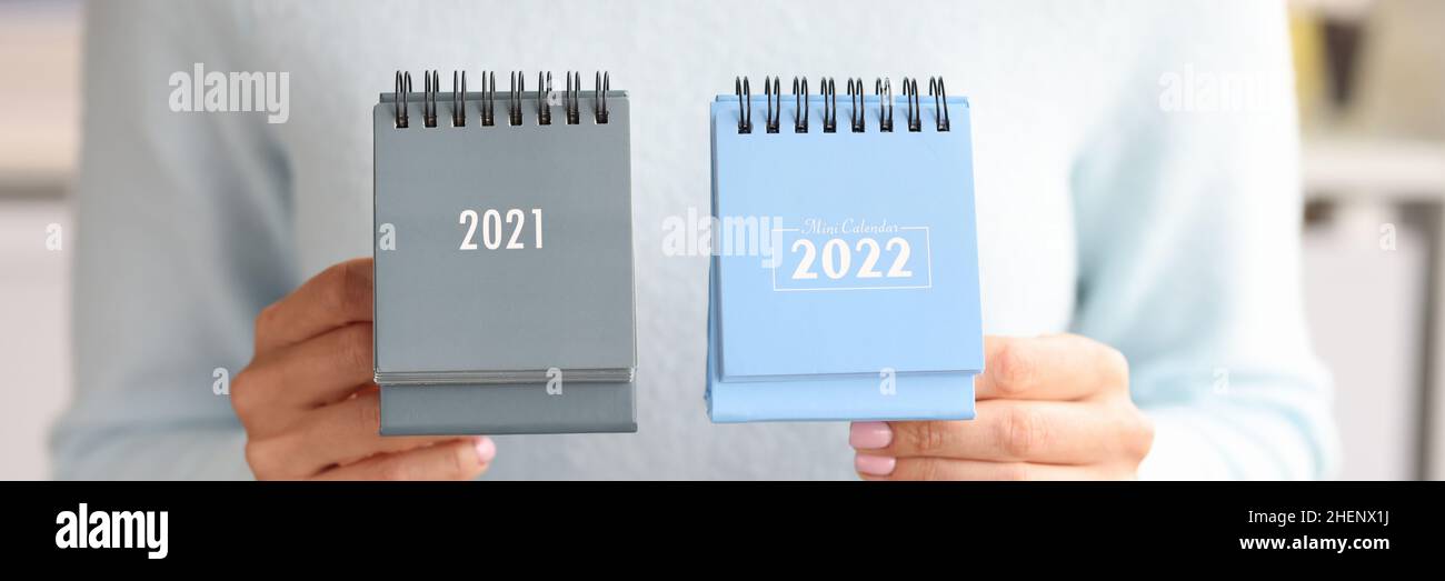 Mujer sosteniendo el calendario 2021 y 2022 cierre. Cambio de año calendario Foto de stock