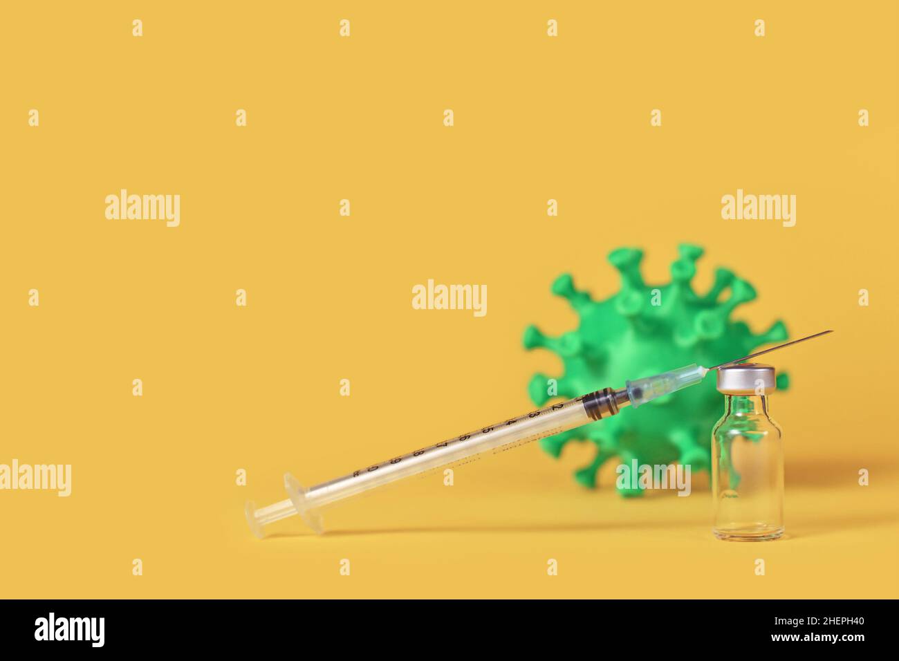 Vial de vacuna Corona con jeringa y modelo de virus en fondo sobre fondo amarillo con espacio de copia Foto de stock