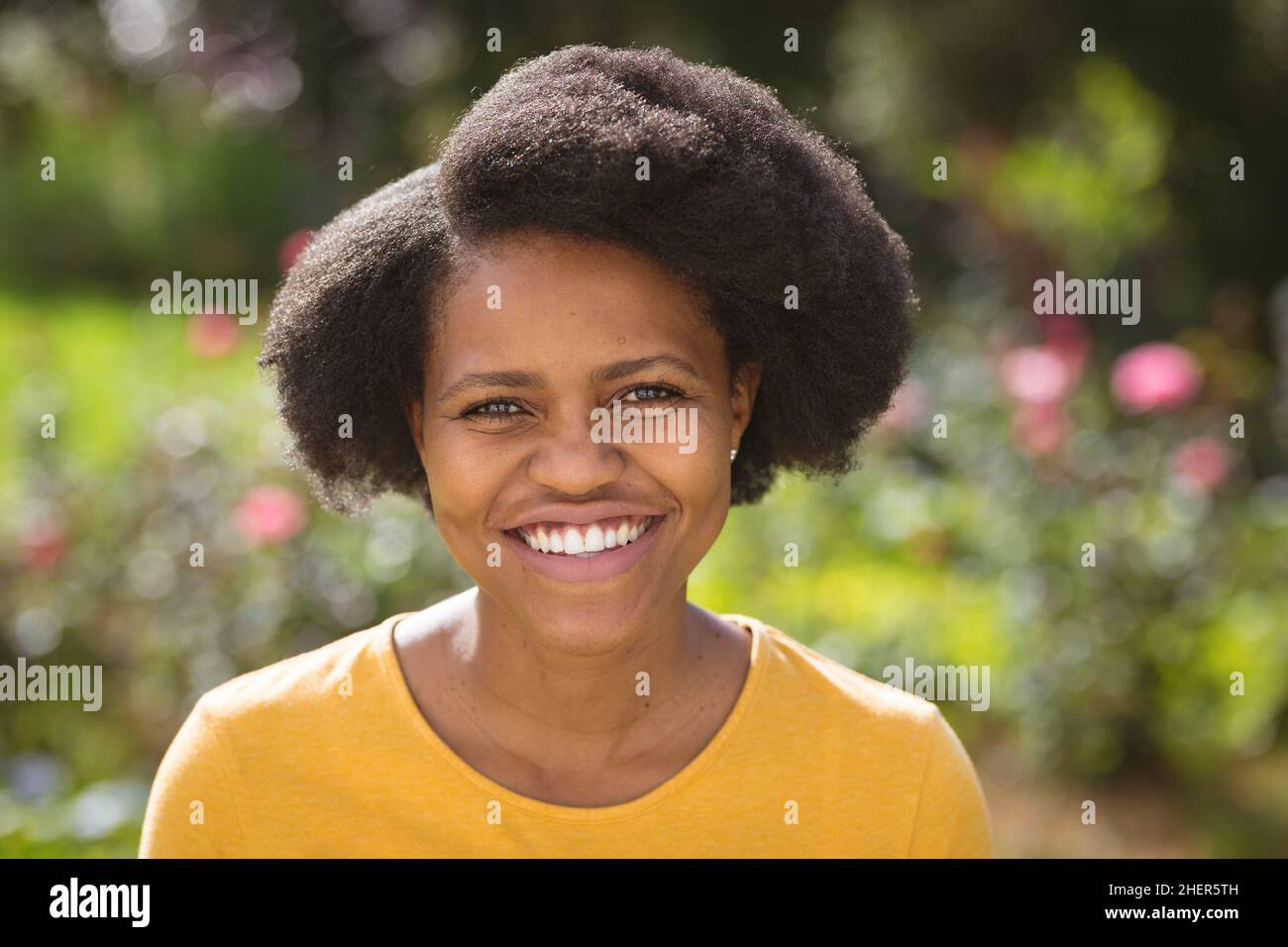 Retrato de la mujer feliz de mediana edad con el peinado afro en el patio trasero en el día soleado Foto de stock