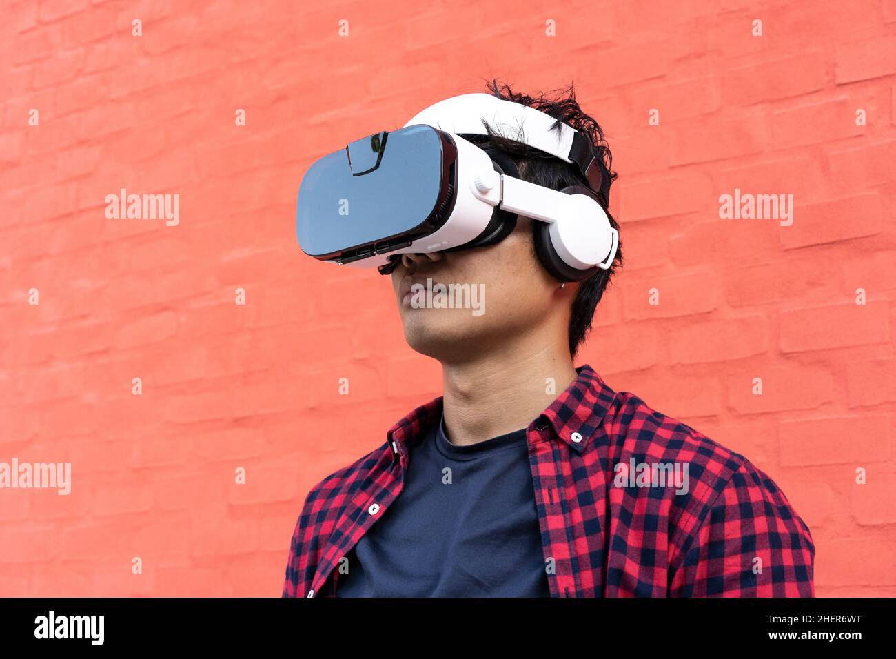 Retrato de un hombre asiático joven aburrido con 3D espectadores con auriculares al aire libre - tecnología y juego de vídeo adicto o futurista concepto Foto de stock