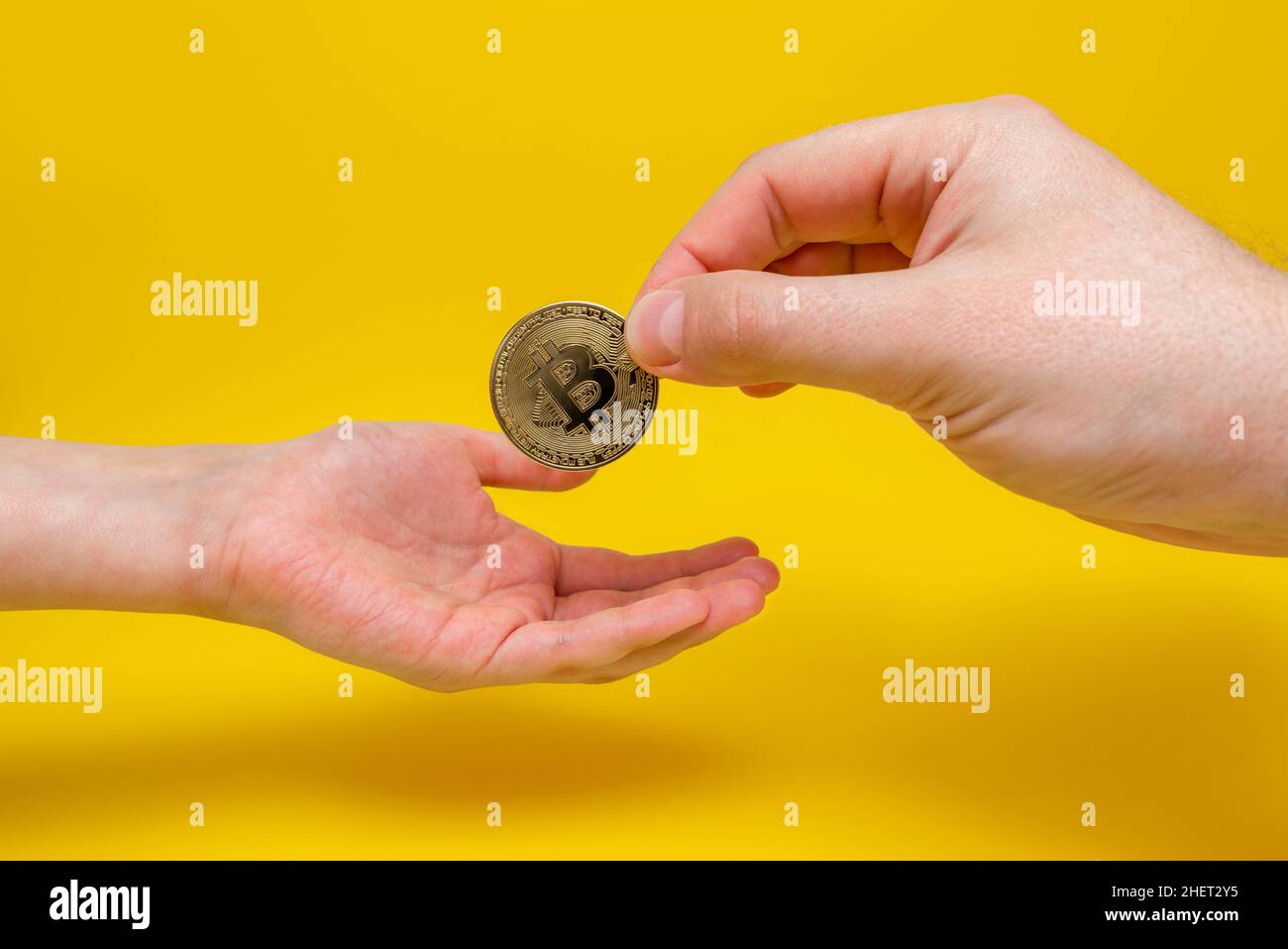 La mano de un adulto pasa un bitcoin dorado a la mano de un niño. El futuro del bitcoin, la inversión en criptomonedas. Bitcoin moneda en la mano del niño Foto de stock