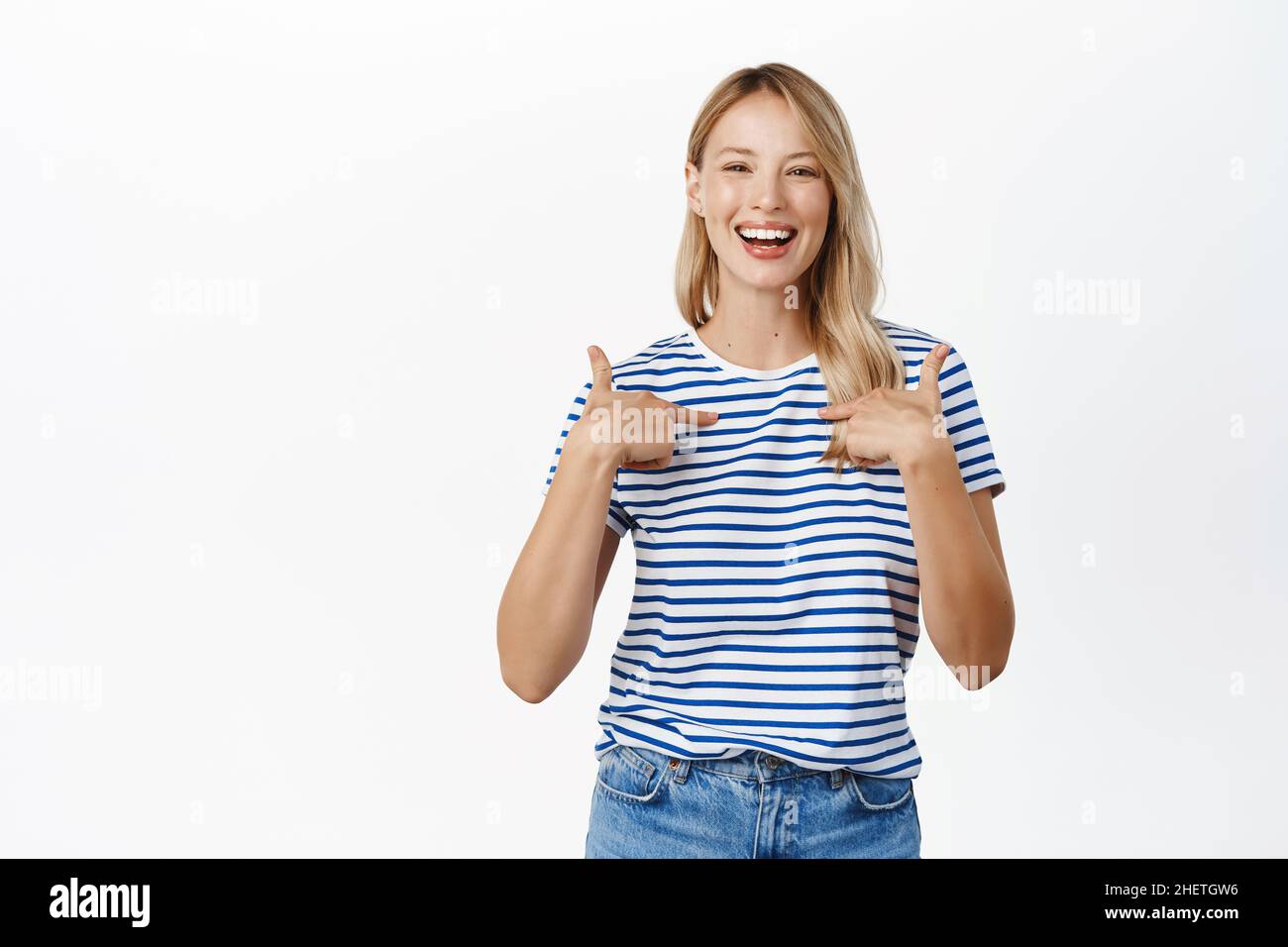 Entusiasta hermosa mujer apuntando los dedos a sí misma, auto-promoción, hablar de logro personal, ganar, sentirse seguro, blanco Foto de stock