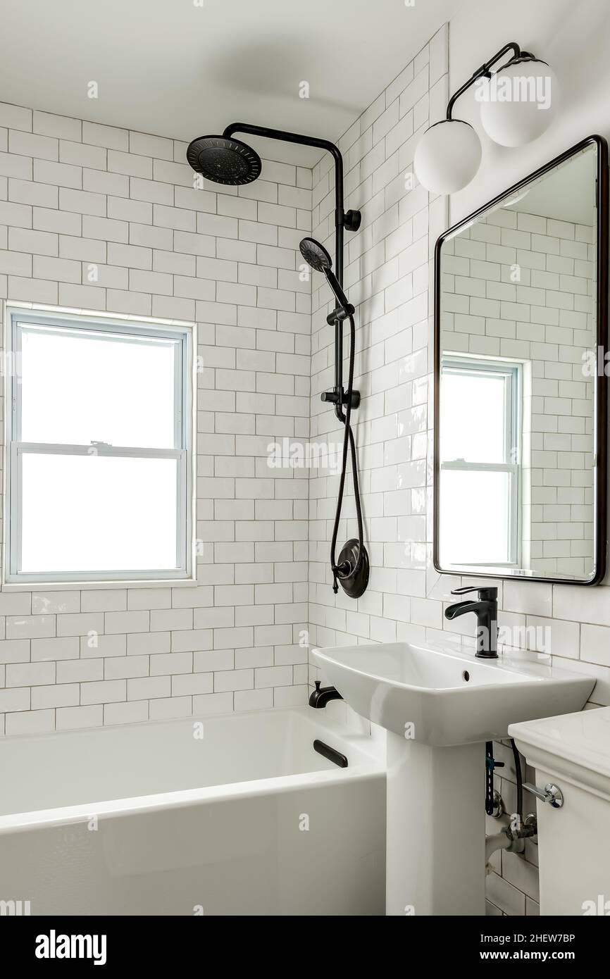 Baño sencillo con ducha negra, espejo redondo y azulejos blancos clásicos  Fotografía de stock - Alamy