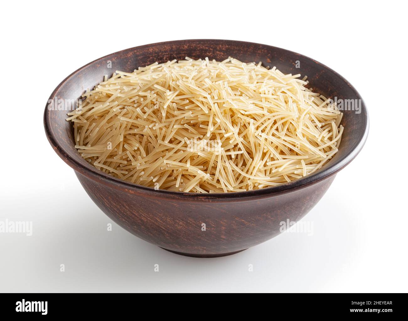 Pasta de vermicelli cruda en cuenco de cerámica aislada sobre fondo blanco con trazado de recorte Foto de stock