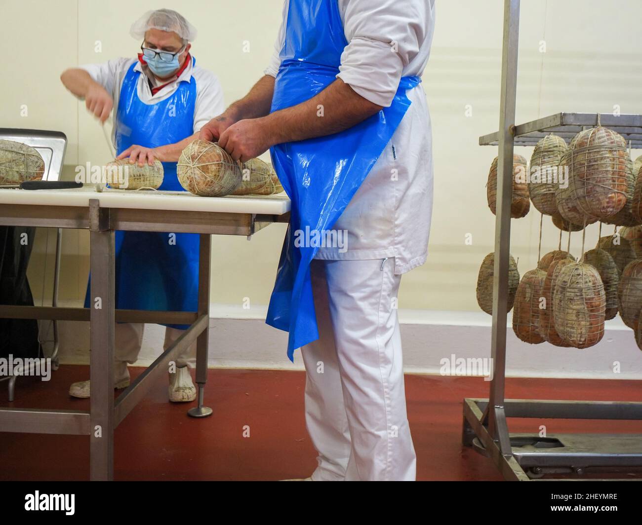 Trabajo especializado coser a mano y terminar culatello, coppa y prosciutto embutidos en planta de fabricación de delicatessen en Parma Italia Foto de stock