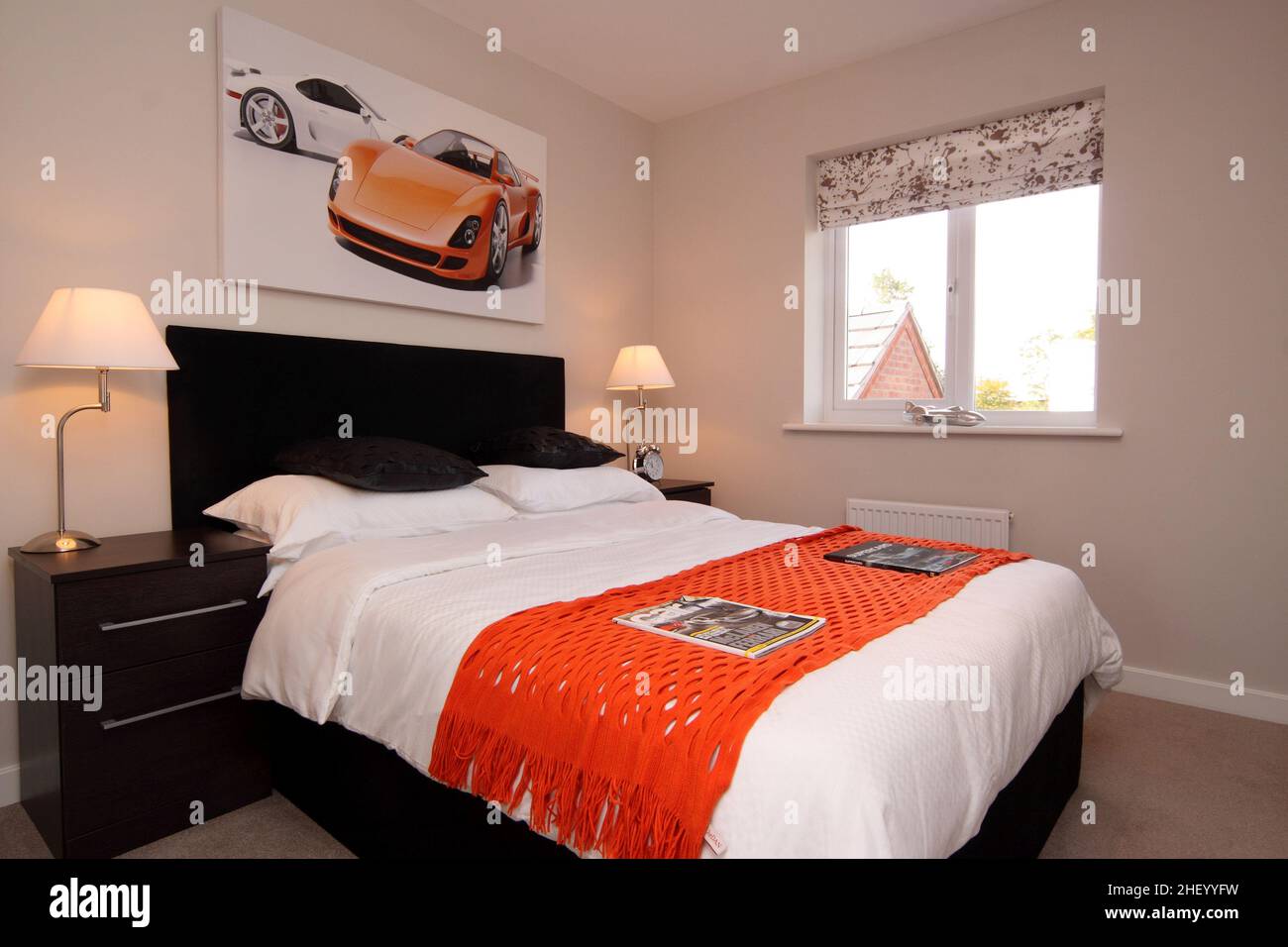 Habitación para niños, temática deportiva de motor de carreras, esquema de colores naranja negro, cama doble king size, luz lateral. Foto de stock