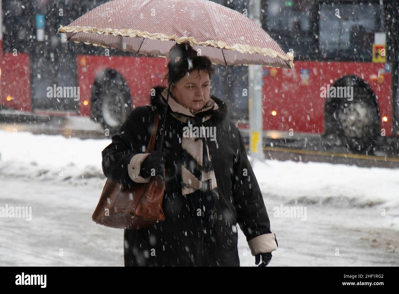 Belgrado, Serbia - 11 de enero de 2022: Una mujer caminando bajo paraguas en un día nevado de invierno en la calle de la ciudad Foto de stock