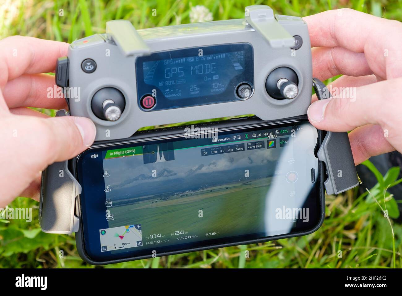 Primer plano del controlador de la consola de drone con el teléfono móvil en manos de hombres con hierba en el fondo. Fotografía aérea de la naturaleza. Enero de 2022, Poprad, Eslovaquia. Foto de stock